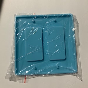 May include: A light blue silicone mold for making two rectangular resin pieces. The mold has four small holes on the edges.