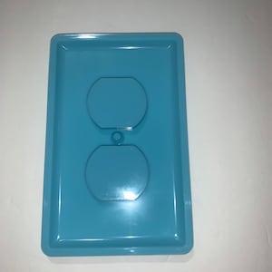 May include: A light blue plastic outlet cover with two round openings for electrical outlets.