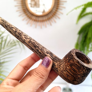 May include: A set of three ceramic mugs with a speckled, cream-coloured glaze. Each mug features a different hand-painted design: a blue and green leaf, a yellow flower, and a red berry. The mugs have a simple, rounded shape.