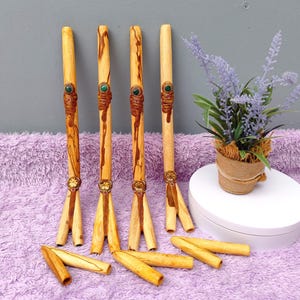 Op de afbeelding: Vier houten wierookhouders met decoratieve gravures en groene steenaccenten. De houders hebben een drietandige basis en worden getoond met extra wierookstokjes en een kleine potplant.