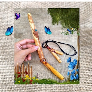 Puede incluir: Varita de madera tallada a mano con una serpiente y adornos turquesa, y un colgante a juego con un cordón negro. La varita es de color marrón claro con vetas de madera natural. Mariposas y flores decorativas rodean la varita.
