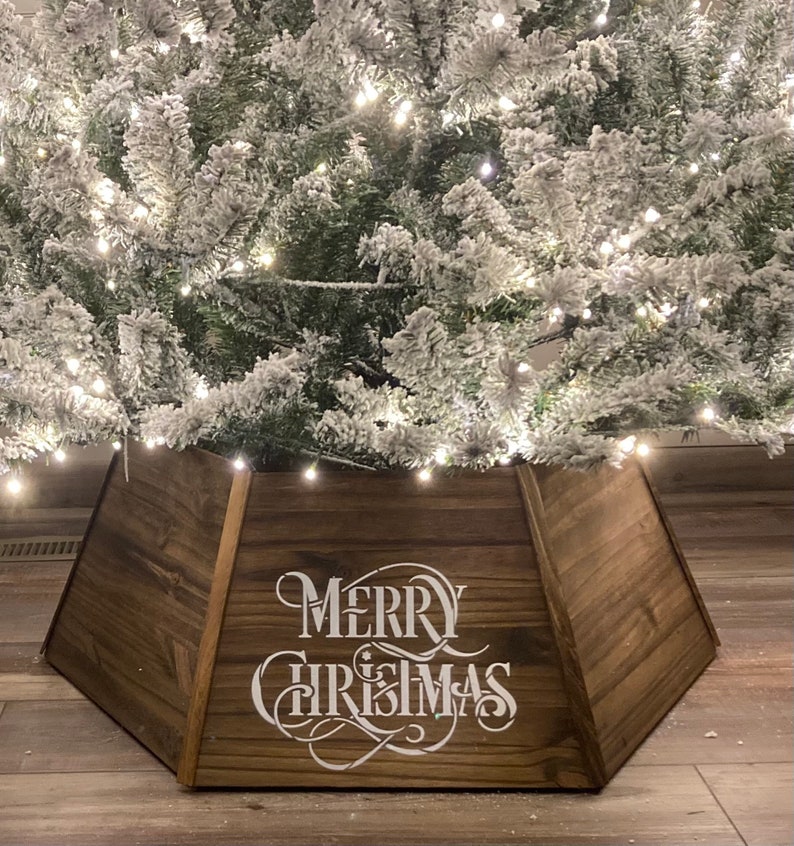 May include: A brown wooden Christmas tree skirt with the words "Merry Christmas" in white lettering.