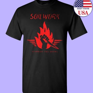 May include: Black t-shirt with a red graphic of a fist holding a knife in a flame with the text "Soilwork" and "Stabbing the Drama" below.