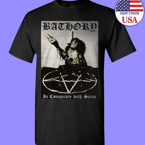 May include: Black and white t-shirt featuring a graphic of a person in a pentagram with the text "Bathory" and "In Conspiracy with Satan".
