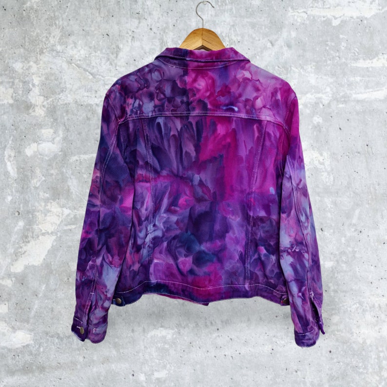 K&ouml;nnte beinhalten: Eine lila und pinkfarbene Batik-Jeansjacke mit Blumenmuster.