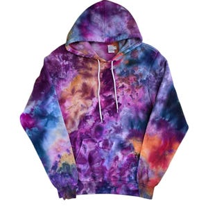 Może przedstawiać: Bluza z kapturem w stylu tie-dye w żywej mieszance kolorów, w tym fioletowym, niebieskim, pomarańczowym i żółtym. Bluza z kapturem posiada przednią kieszeń i biały sznurek. Tkanina ma miękki, teksturowany wygląd.