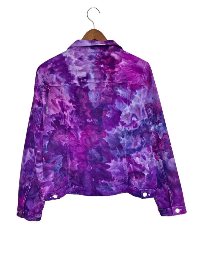 K&ouml;nnte beinhalten: Lilafarbene Batik-Jeansjacke im klassischen Jeansjackenstil.