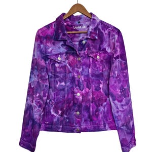 K&ouml;nnte beinhalten: Lilafarbene Batik-Jeansjacke mit einem wei&szlig;en Etikett mit der Aufschrift "LiquidCozy".