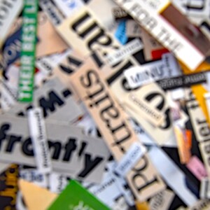 May include: A close-up of a collection of paper scraps with words like "Ready for the", "Potraits", "Expect Better", and "The World" printed on them. The scraps are arranged in a random pattern and are slightly out of focus.