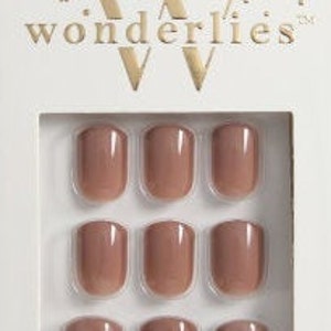 May include: A set of nine glossy, nude-colored press-on nails arranged in a three-by-three grid inside a white cardboard box. The packaging features the gold text "wonderlies" at the top and "MINUTE MANI" at the bottom with gold confetti accents.