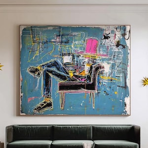 May include: Abstract painting on a blue background depicting a person in a chair, wearing a pink hat. The artwork is framed and hangs above a green velvet sofa and a wooden coffee table. Yellow starburst wall decor.
