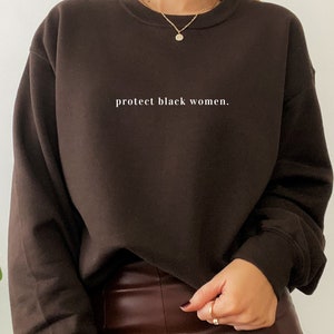 May include: A brown sweatshirt with the text "protect black women." printed in white on the front.