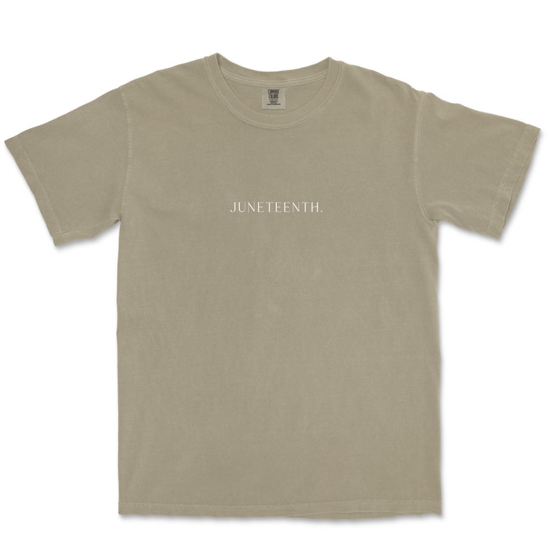 K&ouml;nnte beinhalten: Ein hellbeiges T-Shirt mit dem Aufdruck "JUNETEENTH." in Wei&szlig; auf der Vorderseite.