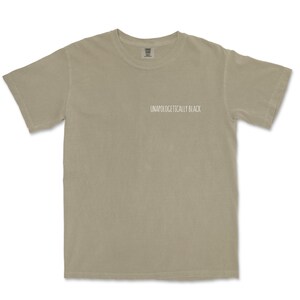 May include: A light gray t-shirt with the text "Unapologetically Black" printed on the front.