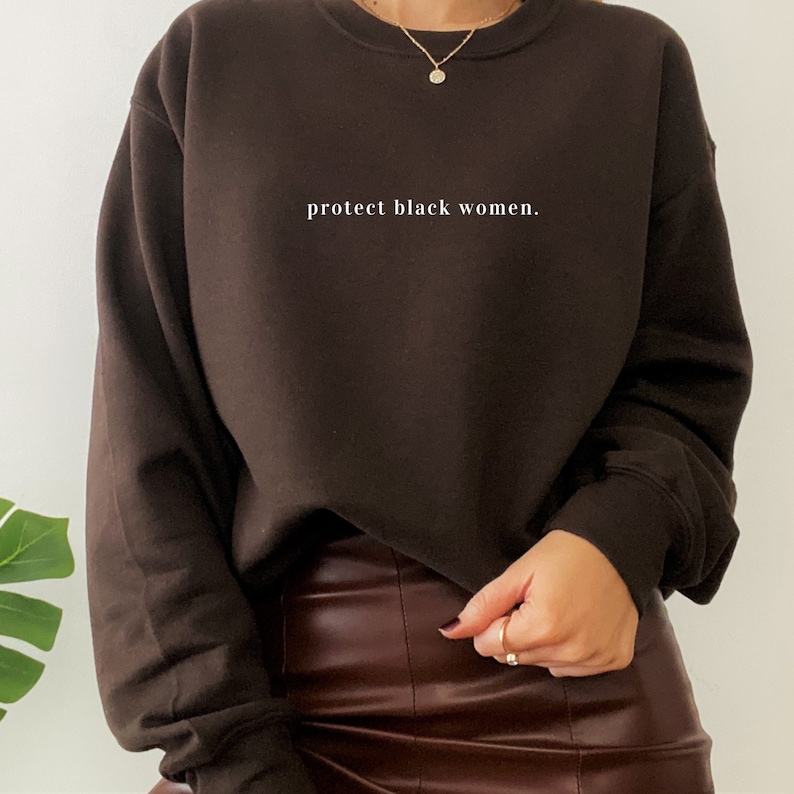 May include: A brown sweatshirt with the text "protect black women." printed in white on the front.