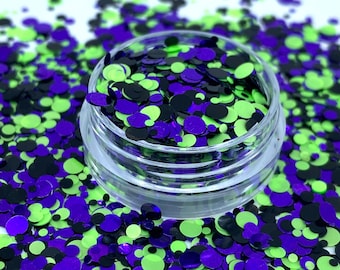 May include: A clear jar filled with green, purple, and black glitter confetti. The confetti is in the shape of circles of varying sizes.