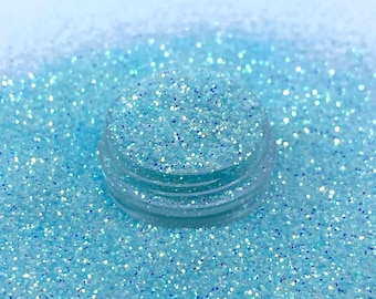 Könnte beinhalten: Nahaufnahme von hellblauem, schimmerndem Glitter, mit einem kleinen Behälter mit Glitter in der Mitte des Bildes.