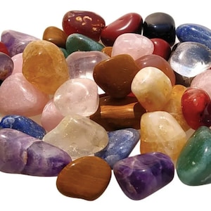 May include: A collection of tumbled stones in various colors, including clear, pink, red, orange, yellow, green, blue, and purple. The stones are smooth and polished, and they are arranged in a circle.