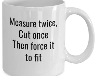 May include: White ceramic coffee mug with black text that reads "Measure twice, Cut once Then force it to fit"