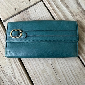 May include: A teal leather wallet with a gold double G logo and a gold buckle closure.