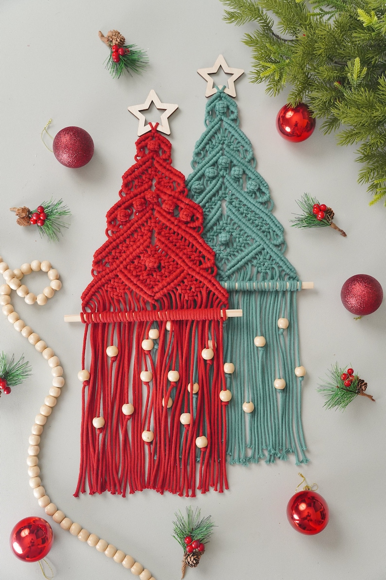 May include: Two macrame Christmas tree wall hangings, one red and one teal, with wooden beads and a star at the top.