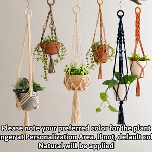 May include: Five macrame plant hangers with different colored cords and wooden beads. The hangers are holding small potted plants. The text "Please note your preferred color for the plant hanger at Personalization Area. If not, default color Natural will be applied" is at the bottom of the image.