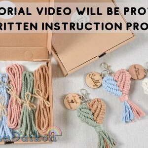 May include: A kit for making macrame heart keychains. The kit includes five spools of colorful string, five metal key rings, and five wooden tags with names. The kit is packaged in a brown cardboard box.  The text "TUTORIAL VIDEO WILL BE PROVIDED NO WRITTEN INSTRUCTION PROVIDED" is printed on the box.
