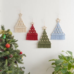 Puede incluir: Cuatro decoraciones de pared de &aacute;rbol de Navidad de macram&eacute; en diferentes colores: blanco, rojo, verde y azul. Cada &aacute;rbol tiene una estrella de madera en la parte superior y cuentas de madera tejidas en el dise&ntilde;o.