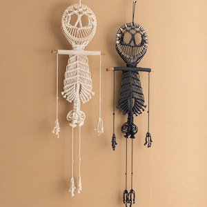 May include: Two macrame wall hangings in the shape of a skeleton. One is white and the other is black.