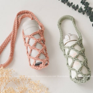 Puede incluir: Dos porta botellas de ganchillo con correas. Uno es rosa y el otro es verde. Ambos porta botellas están hechos con un patrón de punto simple y tienen un aspecto tejido.