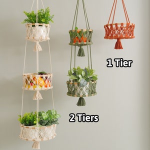 May include: Three macrame plant hangers with different tiers. The top hanger has one tier, the middle hanger has two tiers, and the bottom hanger has three tiers. Each tier has a woven basket with a plant inside. The hangers are made of natural colored rope with tassels.