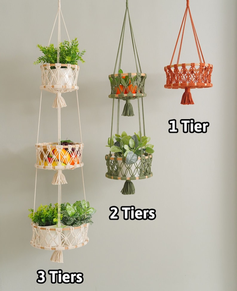May include: Three macrame plant hangers with different tiers. The top hanger has one tier, the middle hanger has two tiers, and the bottom hanger has three tiers. Each tier has a woven basket with a plant inside. The hangers are made of natural colored rope with tassels.