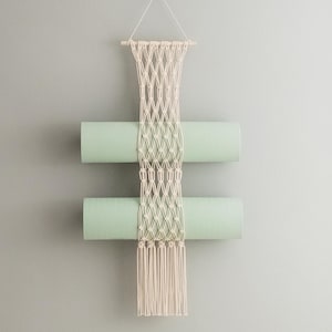Peut inclure: Une suspension murale en macramé avec deux tapis de yoga vert clair suspendus. Le macramé est fait de corde de coton naturelle et a une frange en bas.