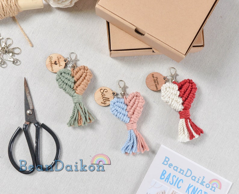 May include: Three handmade macrame heart keychains with wooden tags. The keychains are in different colors: green and beige, blue and pink, and red and white. The wooden tags have personalized text.
