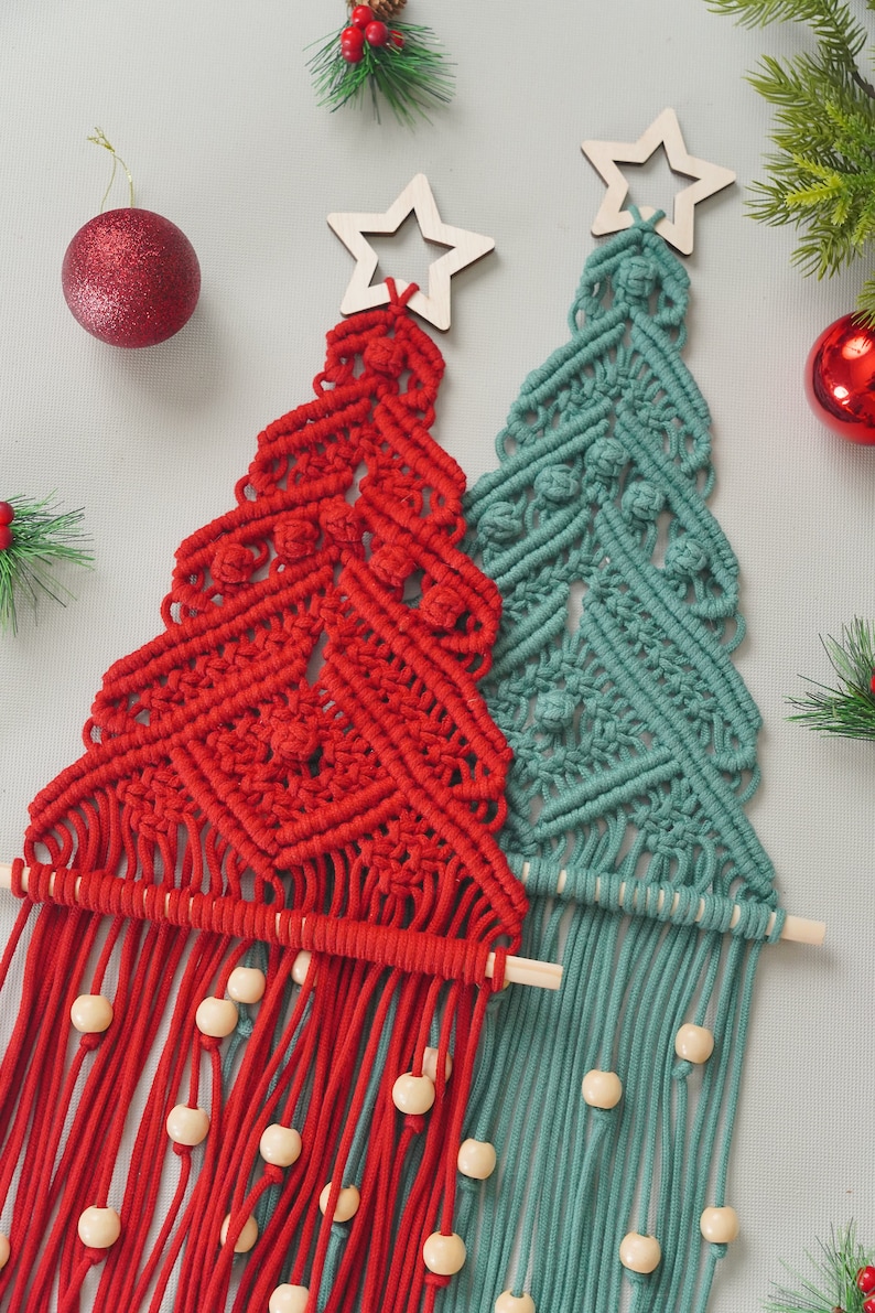 May include: Two macrame Christmas tree wall hangings, one red and one teal green, with wooden star toppers and wooden bead accents.