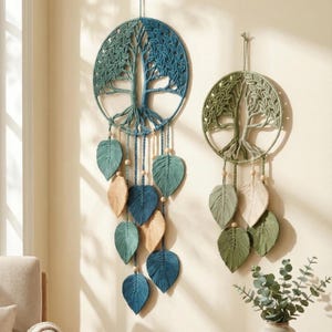 Op de afbeelding: Twee macramé wandkleden met levensboomontwerpen. Eén is blauw en blauwgroen, de andere groen en crème. Beide hebben bladvormige accenten en houten kralen, wat een natuurlijke, bohemien touch aan de woondecoratie geeft.
