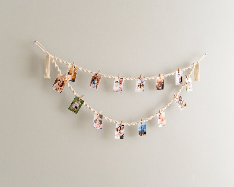 Peut inclure: Une guirlande de ficelle blanche avec des glands &agrave; chaque extr&eacute;mit&eacute;, tenant des photos de personnes avec des pinces &agrave; linge. Les photos sont dispos&eacute;es en ligne courbe.