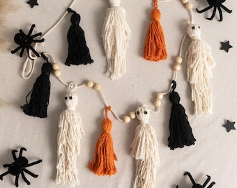 Peut inclure: Une guirlande sur le thème d'Halloween avec des figurines de fantômes et des pompons noirs et orange faits à la main. La guirlande est ornée de perles en bois et comprend des décorations d'étoiles et d'araignées noires.
