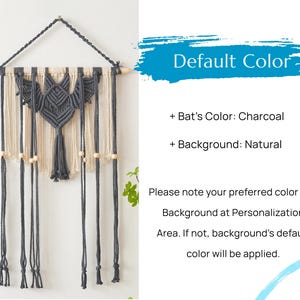 May include: A charcoal gray bat macrame wall hanging with a natural colored background. The bat has a small red bead for an eye. The hanging has wooden beads and tassels.