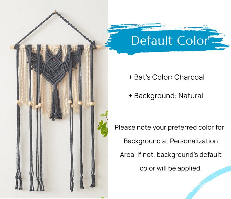 May include: A charcoal gray bat macrame wall hanging with a natural colored background. The bat has a small red bead for an eye. The hanging has wooden beads and tassels.