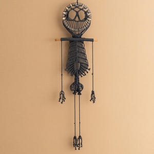 May include: Black macrame wall hanging with a circular skull design and tassels.