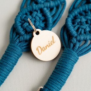May include: A teal blue macrame dog leash with a wooden tag that says "Daniel" attached to it.