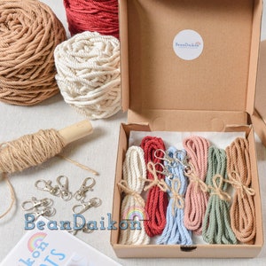 May include: A set of six colorful cotton cords with metal clasps in a cardboard box. The cords are red, light blue, pink, green, and beige. The box has a label that says "BeanDaikon".