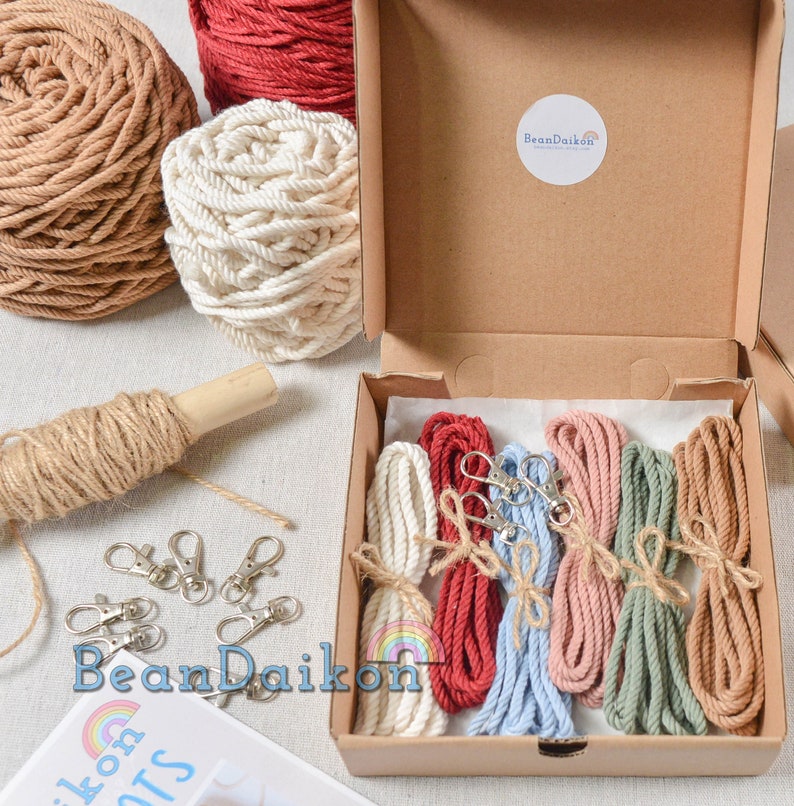 May include: A set of six colorful cotton cords with metal clasps in a cardboard box. The cords are red, light blue, pink, green, and beige. The box has a label that says "BeanDaikon".