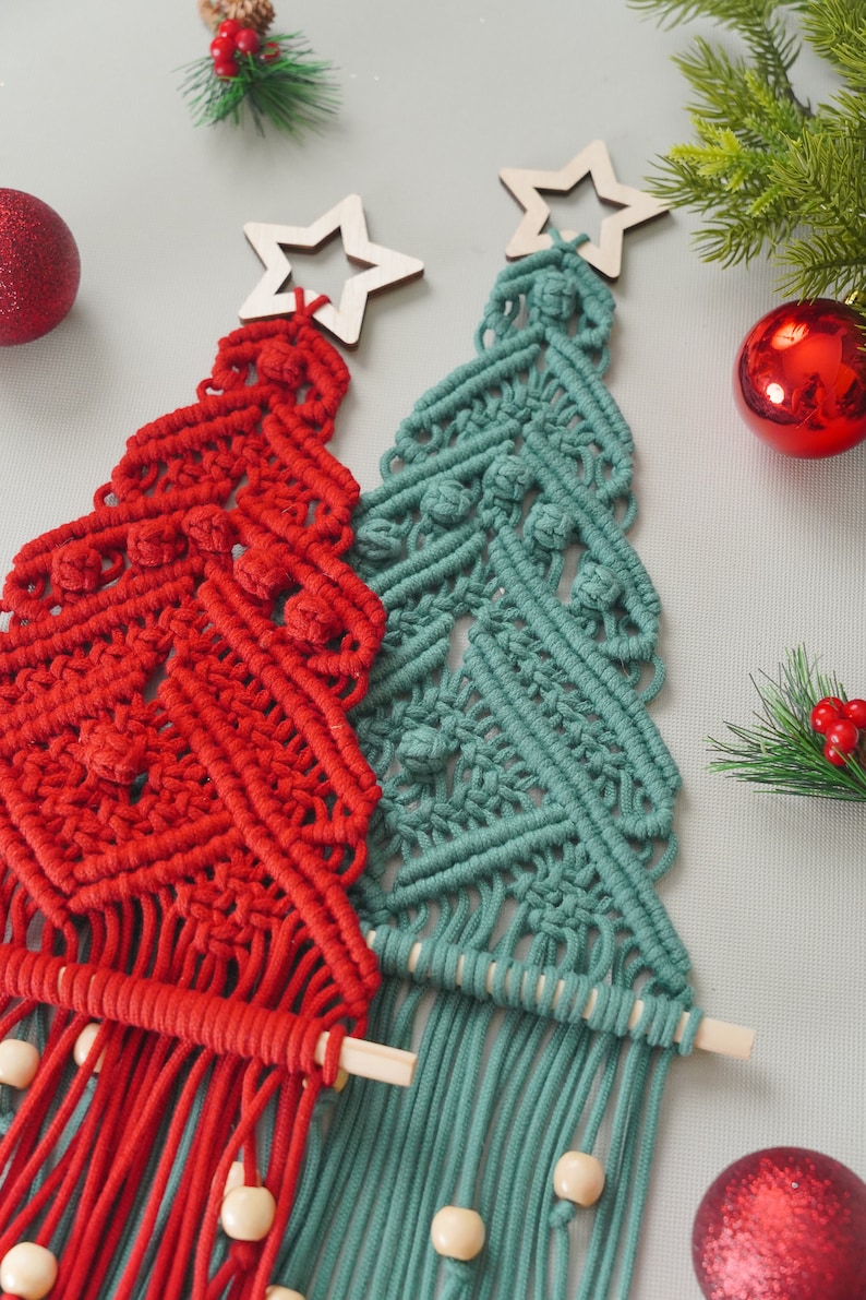 May include: Two macrame Christmas trees, one red and one teal, with wooden stars on top and wooden beads on the bottom.