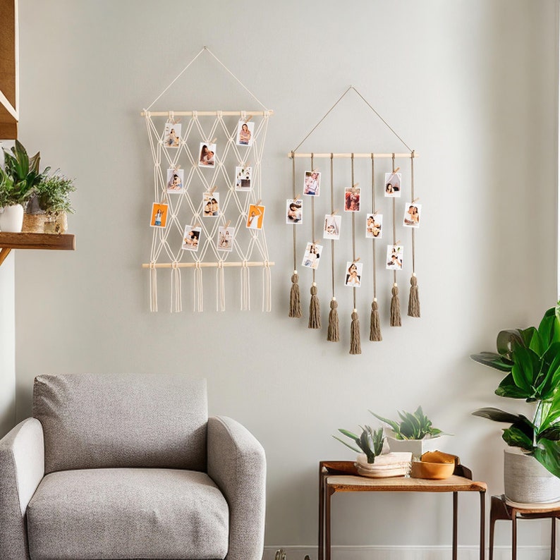 Pode incluir: Dois expositores de fotos de macram&eacute; com ripas de madeira e borlas. O expositor &agrave; esquerda &eacute; branco e tem um padr&atilde;o de grade. O expositor &agrave; direita &eacute; castanho e tem um design em cascata. Ambos os expositores est&atilde;o pendurados numa parede branca.