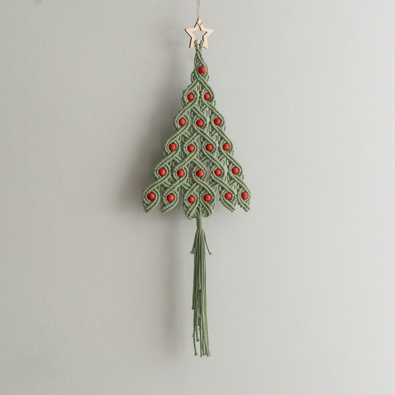 May include: A green macrame Christmas tree ornament with red beads and a wooden star on top. The ornament has a long green tassel.