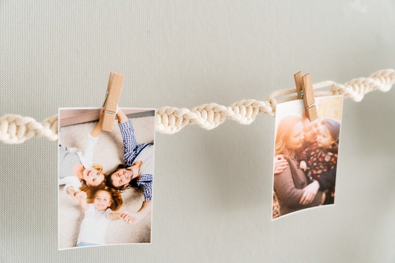Peut inclure: Deux photos sont accroch&eacute;es &agrave; un mur blanc avec une corde blanche. La photo de gauche montre une famille de trois personnes allong&eacute;es sur le sol, souriant et se tenant la main. La photo de droite montre une femme et deux enfants qui s'embrassent dans un parc.