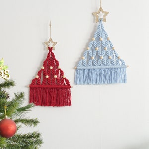 Puede incluir: Dos decoraciones de pared de macram&eacute; en forma de &aacute;rbol de Navidad, una roja y otra azul claro, con cuentas de madera y una estrella de madera en la parte superior.