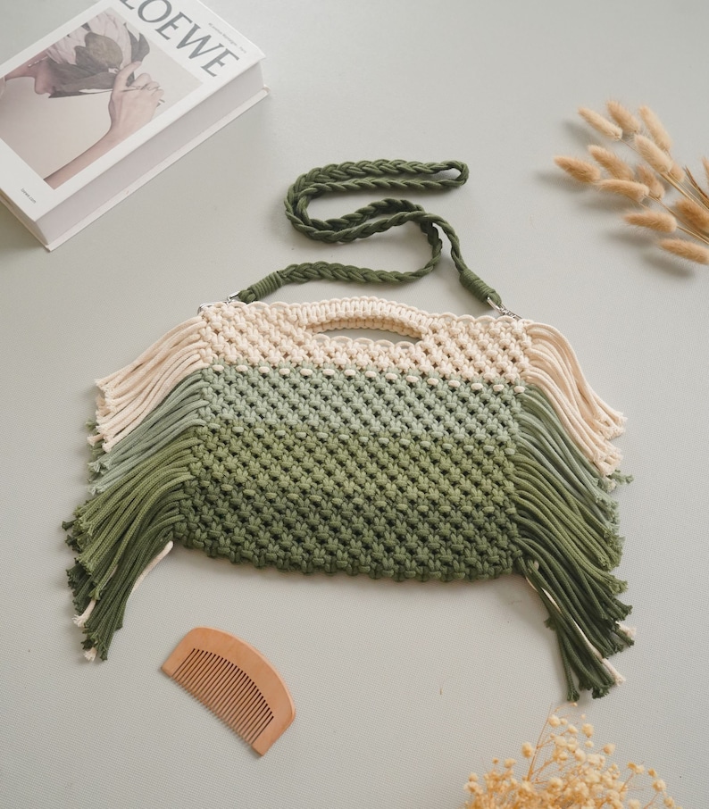 May include: A green, white, and cream crocheted bag with a long green strap and fringe details.